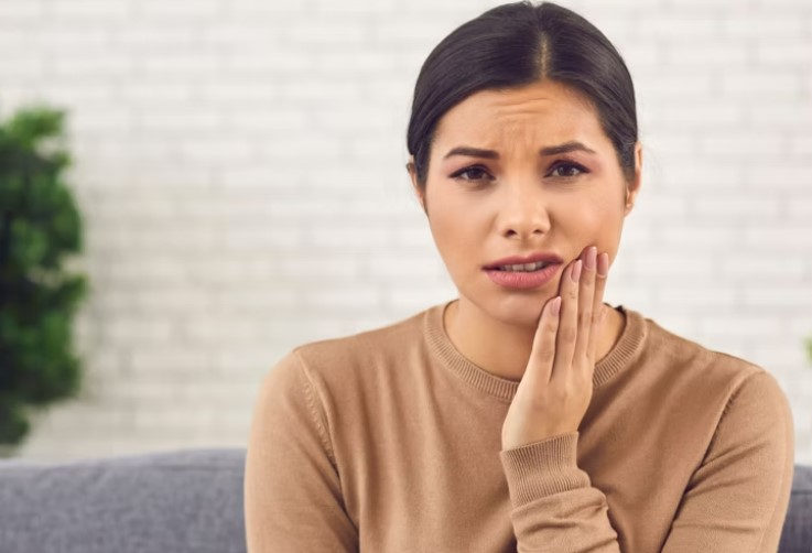 A woman holding her cheek with toothache